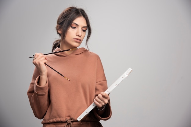 Free photo young beautiful artist holding paint brush and canvas