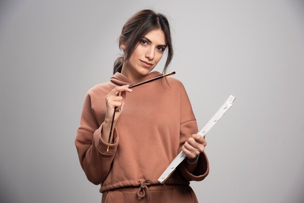 Young beautiful artist holding paint brush and canvas