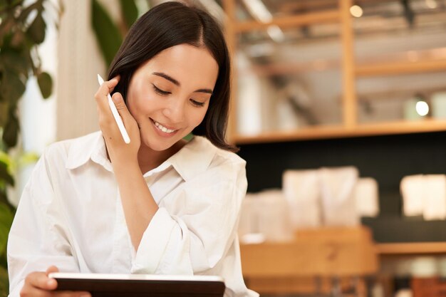 Young beautiful artist woman drawing on tablet with graphic pen smiling happily