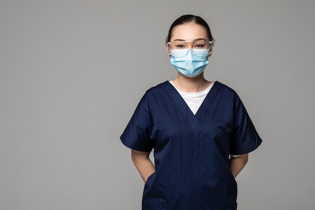 Young beautiful Asian Chinese medicine doctor woman or hospital nurse in scrubs using protective medical face mask in prevention against virus infection