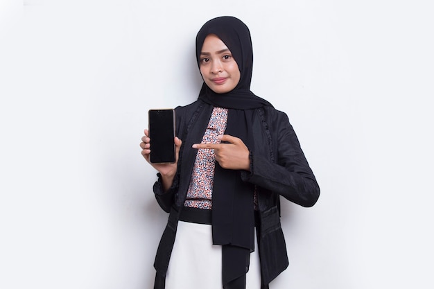 Young beautiful asian muslim woman demonstrating mobile cell phone isolated on white background