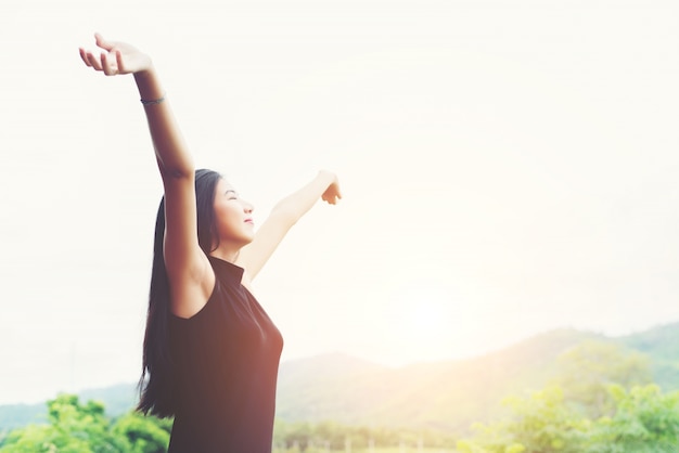 Young beautiful asian woman standing raising hands to relaxing w