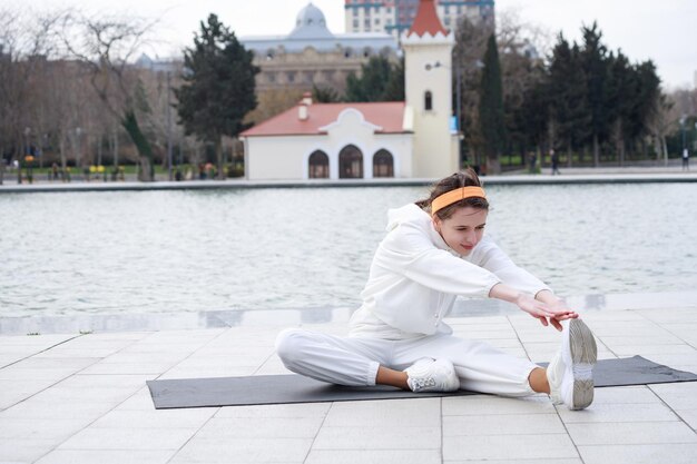 Young beautiful athlete sitting on the yoga mat and stretching her body High quality photo