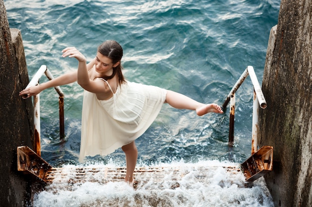 Бесплатное фото Молодая красивая балерина танцует и позирует на улице