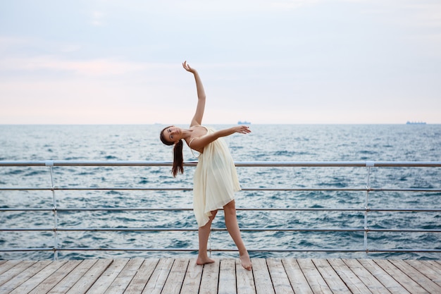 Бесплатное фото Молодая красивая балерина танцует и позирует на улице