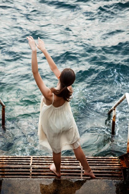 Young beautiful ballerina dancing and posing outside sea background