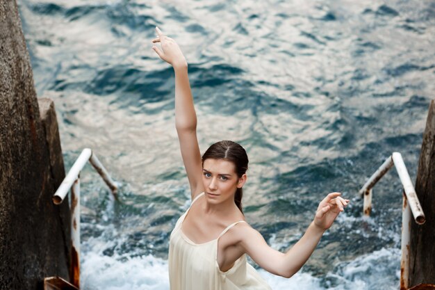 Young beautiful ballerina dancing and posing outside, sea wall