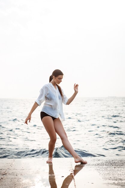 Young beautiful ballerina dancing and posing outside, sea wall