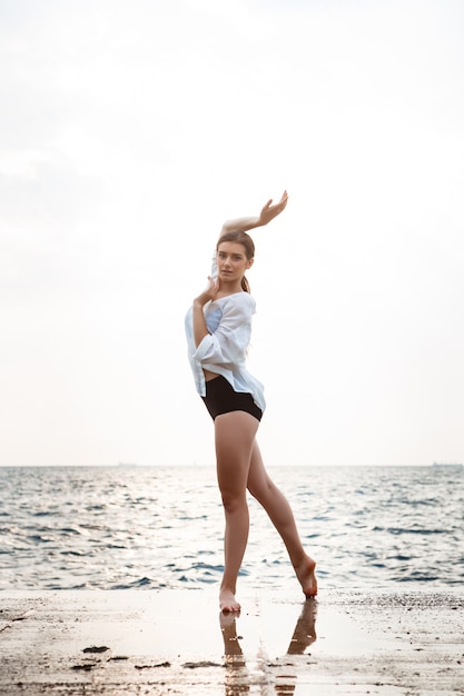 Young beautiful ballerina dancing and posing outside, sea wall