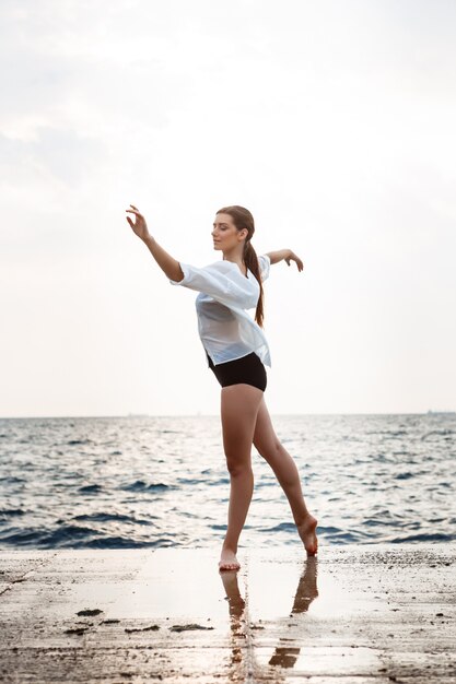 Young beautiful ballerina dancing and posing outside