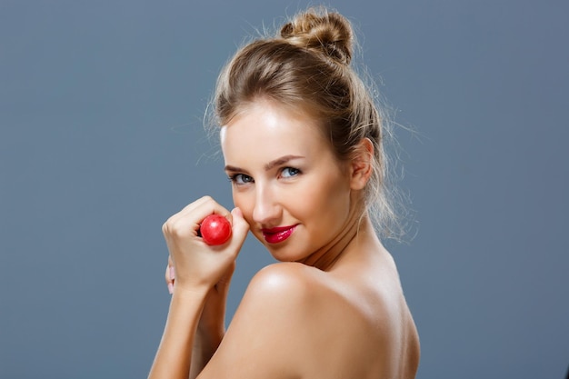 Free photo young beautiful blonde girl holding chupa chups over grey background