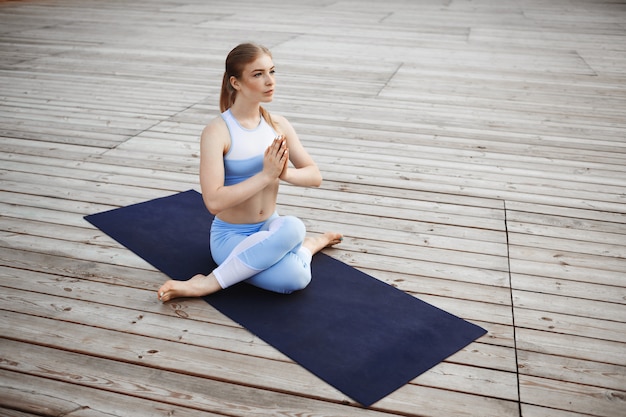 Young beautiful blonde girl practicing yoga outside.