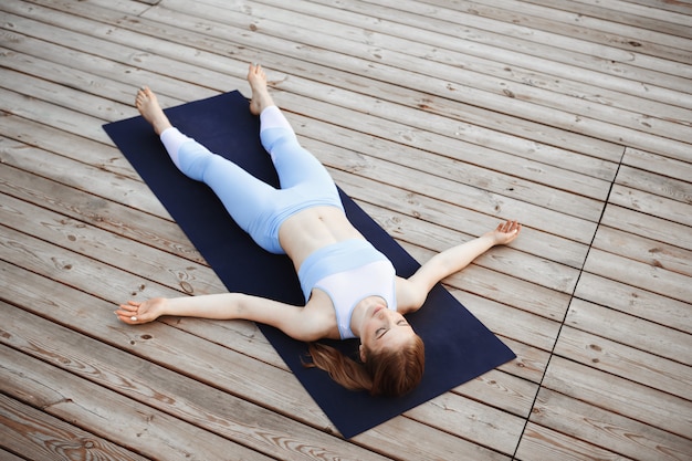 Young beautiful blonde girl practicing yoga outside.