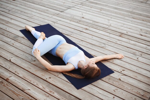 Young beautiful blonde girl practicing yoga outside.