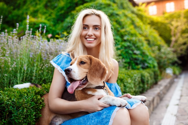 ウォーキング、公園でビーグル犬と遊ぶ若い美しいブロンドの女の子。