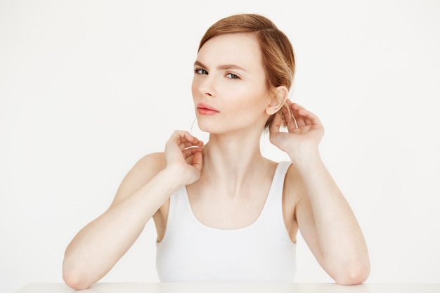 Young beautiful blonde girl with clean fresh skin sitting at table  correcting hairstyle. Beauty and spa.