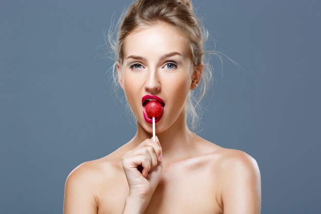 ロリポップを食べる若い美しいブロンドの女性