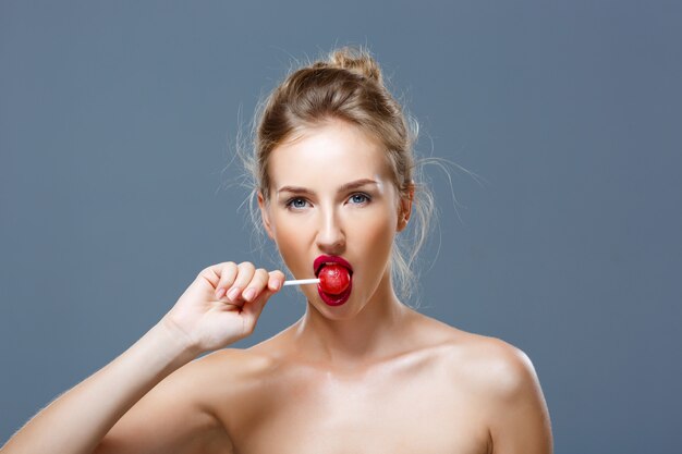 Young beautiful blonde woman eating lollipop