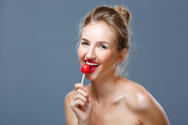 Young beautiful blonde woman eating lollipop