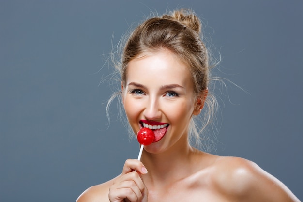 Young beautiful blonde woman eating lollipop