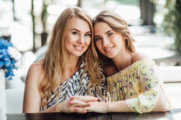 Молодая красивая блондинка и ее хорошенькая мама отдыхают на летней террасе кафе