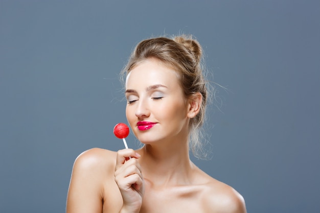 Young beautiful blonde woman holding lollipop