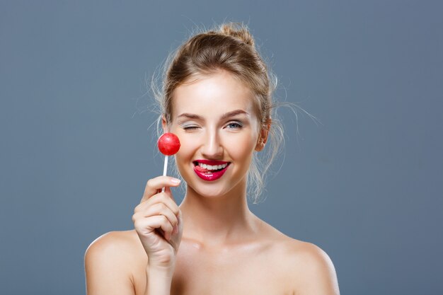 Young beautiful blonde woman holding lollipop