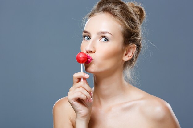 Young beautiful blonde woman kissing lollipop