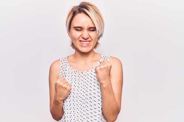 Free photo young beautiful blonde woman wearing casual clothes celebrating surprised and amazed for success with arms raised and eyes closed