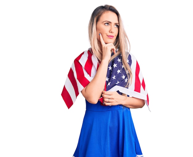 Free photo young beautiful blonde woman wearing cheerleader uniform and united states flag serious face thinking about question with hand on chin, thoughtful about confusing idea