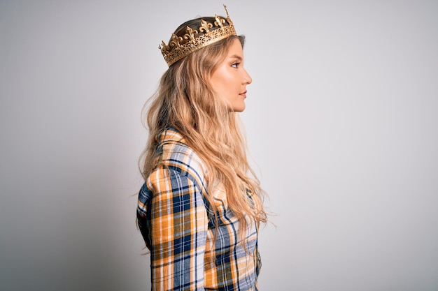 Free photo young beautiful blonde woman wearing golden crown of queen over isolated white background looking to side relax profile pose with natural face with confident smile