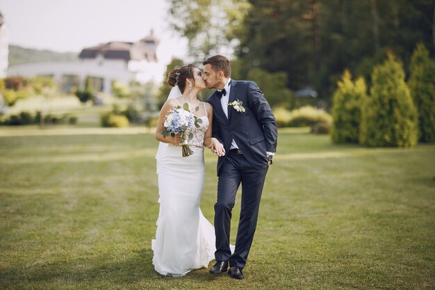Молодая и красивая невеста и ее муж, стоя в парке с букетом цветов