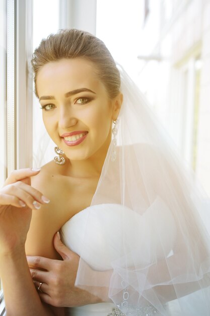 Young beautiful bride posing against the window in the hotel room