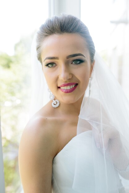 Young beautiful bride posing against the window in the hotel room