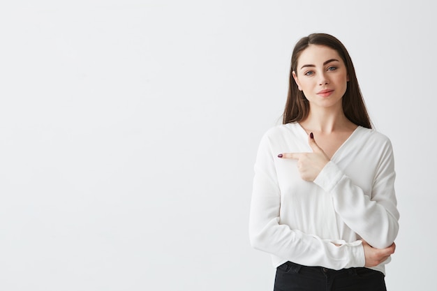 Young beautiful brunette businesswoman smiling pointing finger in side .