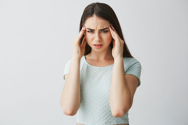 Free photo young beautiful brunette girl frowning touching temples. headache. isolated on white background.