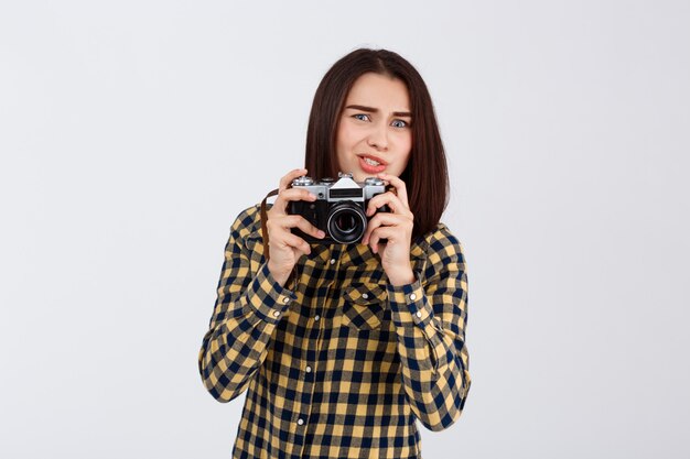 Young beautiful brunette photographer over white wall.