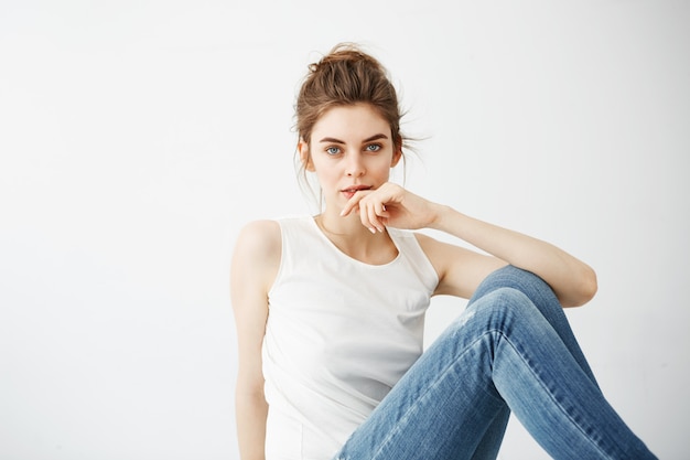 Free photo young beautiful brunette woman with bun smiling sitting over white background.