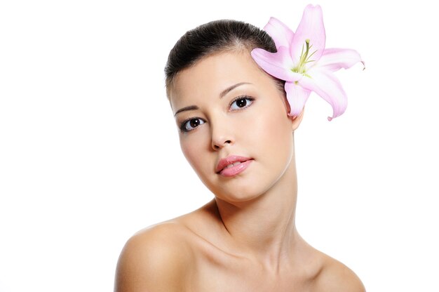 Young Beautiful brunette woman with a lily from her ear over white