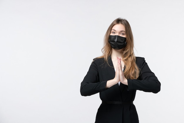 Young beautiful business lady in suit wearing surgical mask and making thanks gesture on isolated white wall