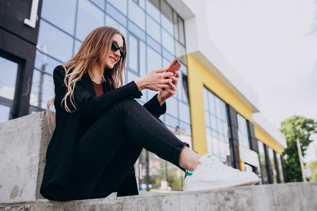 Young beautiful business woman by the office center,using phone