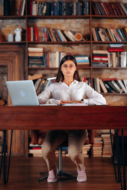 Young beautiful business woman in glasses sits at a work table