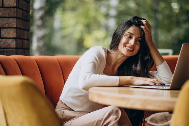 Giovane bella donna d'affari che lavora al computer in un caffè