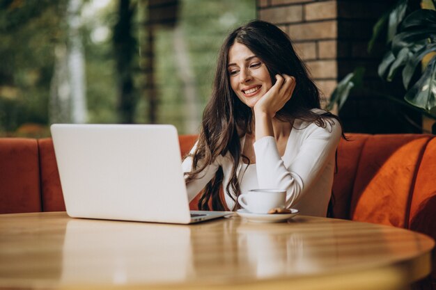 カフェでコンピューターに取り組んでいる若い美しいビジネス女性