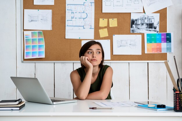 Young beautiful businesswoman dreaming, sitting at workplace with laptop