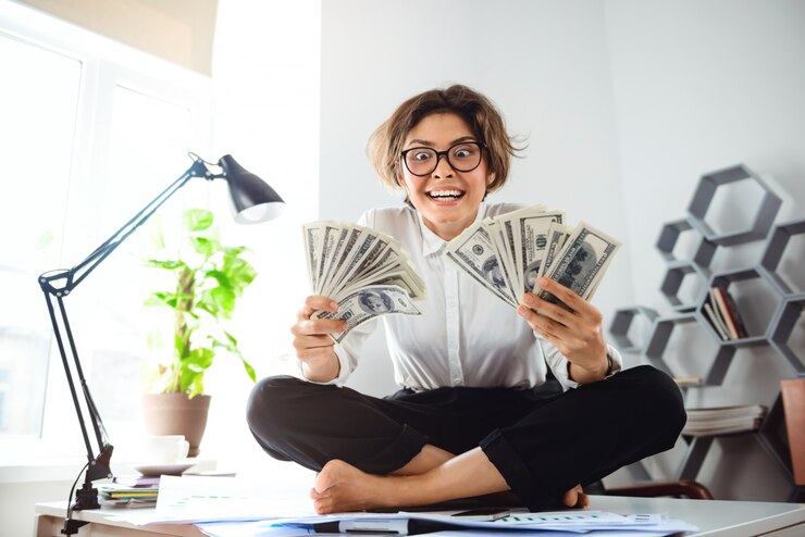 Free Photo young beautiful businesswoman holding money, sitting on table at workplace.
