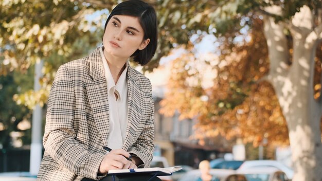 Young beautiful businesswoman looking thoughtful sitting on street and working Freelancer girl working outdoor