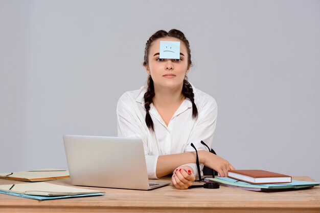 Young beautiful businesswoman sitting with sticker on forehead at workplace