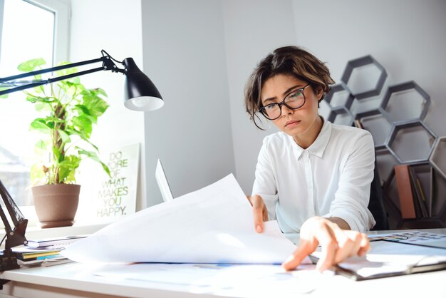 Young beautiful businesswoman sitting at workplace in office.