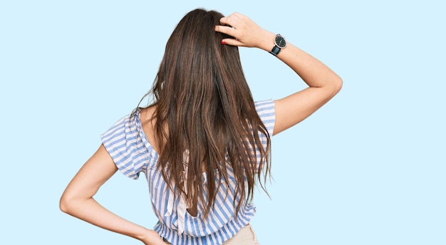 Young beautiful caucasian girl wearing casual clothes backwards thinking about doubt with hand on head